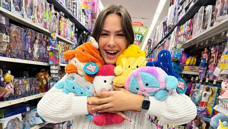 Gen Z teen surrounded by plush toys in store, showcasing how young families prioritize fun and affordable purchases.